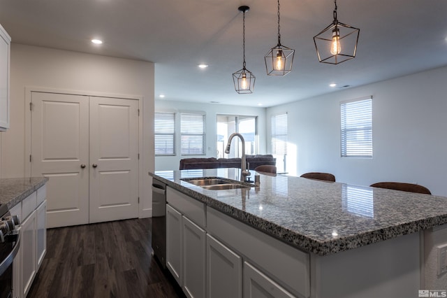 kitchen featuring stainless steel appliances, an island with sink, sink, and decorative light fixtures