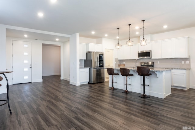 kitchen with pendant lighting, tasteful backsplash, a kitchen breakfast bar, stainless steel appliances, and a center island with sink