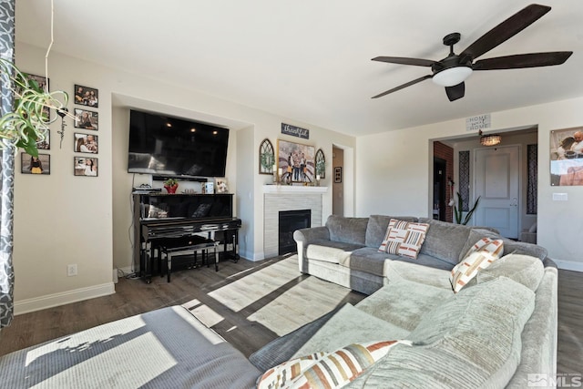 living room featuring a brick fireplace, dark wood-type flooring, and ceiling fan