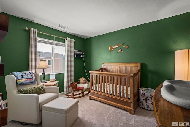 bedroom with a nursery area and carpet