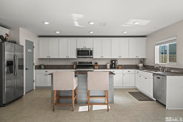 kitchen with sink, a breakfast bar area, a center island, appliances with stainless steel finishes, and white cabinets