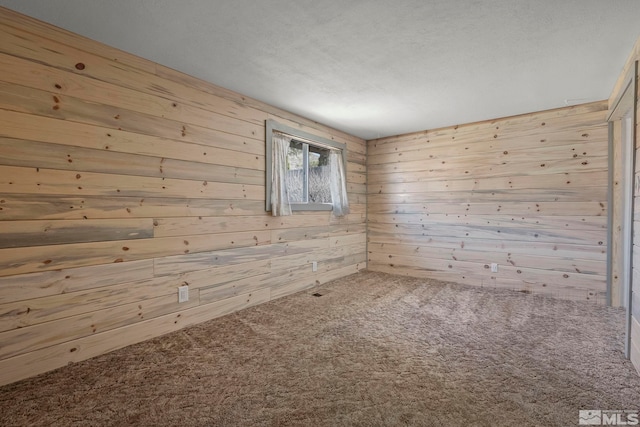 carpeted empty room featuring wooden walls