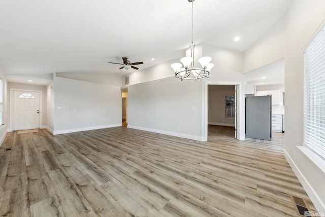 unfurnished living room featuring lofted ceiling, ceiling fan with notable chandelier, and light hardwood / wood-style floors