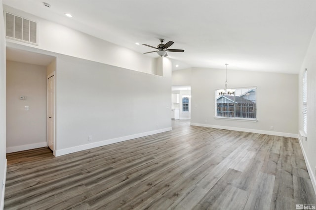 unfurnished living room featuring wood-type flooring, vaulted ceiling, and ceiling fan with notable chandelier