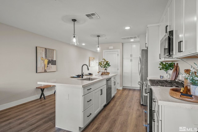 kitchen featuring pendant lighting, sink, appliances with stainless steel finishes, a kitchen island with sink, and white cabinets