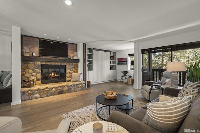 living room with a stone fireplace and hardwood / wood-style floors