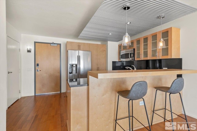 kitchen with a breakfast bar area, decorative light fixtures, dark hardwood / wood-style flooring, kitchen peninsula, and stainless steel appliances