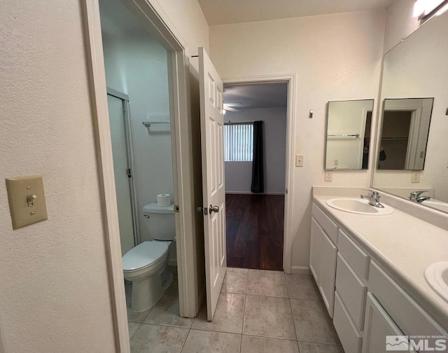 bathroom featuring tile patterned flooring, vanity, toilet, and an enclosed shower