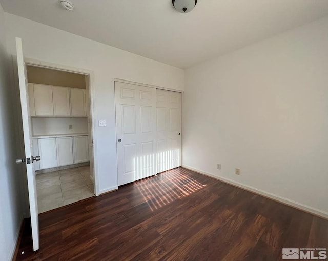 unfurnished bedroom with dark hardwood / wood-style floors and a closet