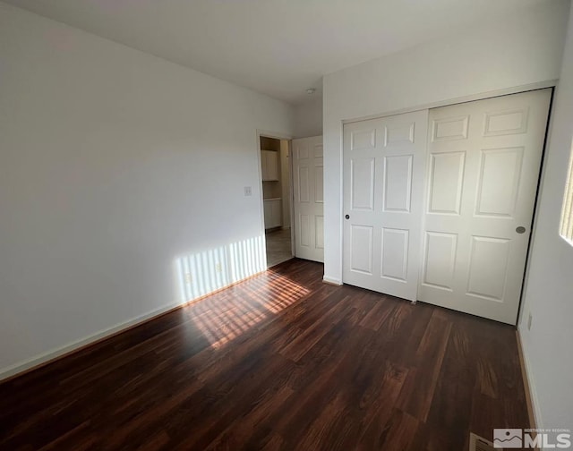 unfurnished bedroom featuring dark wood-type flooring and a closet