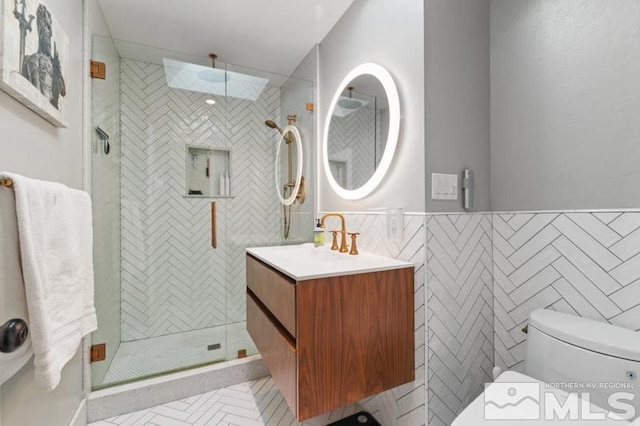 bathroom featuring tile walls, vanity, toilet, and an enclosed shower