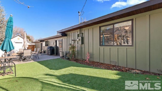 back of house with a patio and a lawn