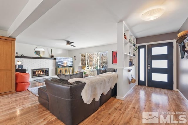 living room with a fireplace, light hardwood / wood-style flooring, and ceiling fan