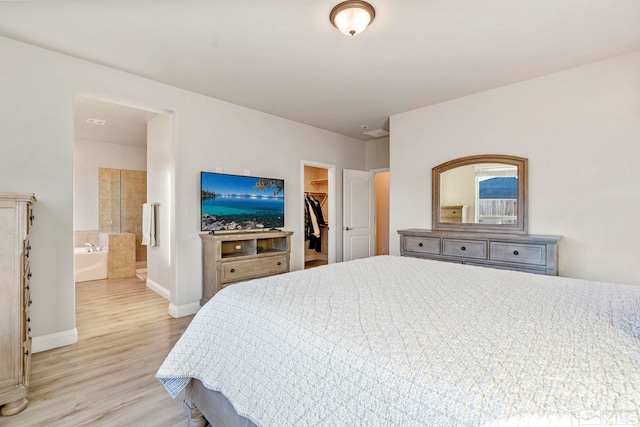 bedroom with connected bathroom, a walk in closet, light hardwood / wood-style floors, and a closet