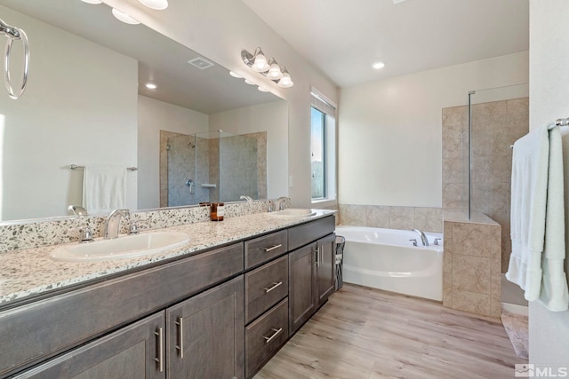 bathroom featuring hardwood / wood-style flooring, vanity, and plus walk in shower