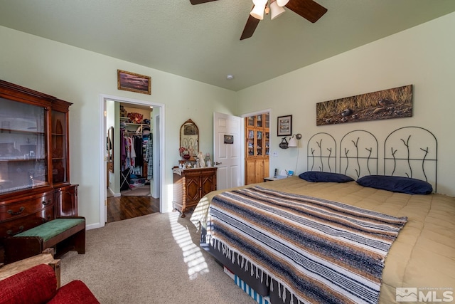 bedroom featuring a walk in closet, carpet floors, a closet, and ceiling fan