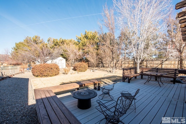 deck with a shed and an outdoor fire pit