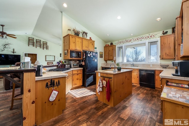 kitchen featuring an island with sink, lofted ceiling, sink, a breakfast bar area, and black appliances