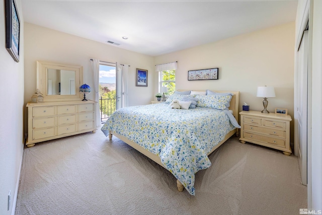 bedroom with access to outside, light colored carpet, and a closet