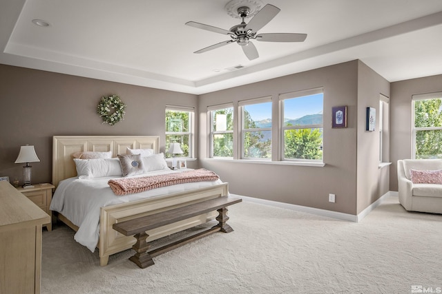 carpeted bedroom featuring ceiling fan and a tray ceiling