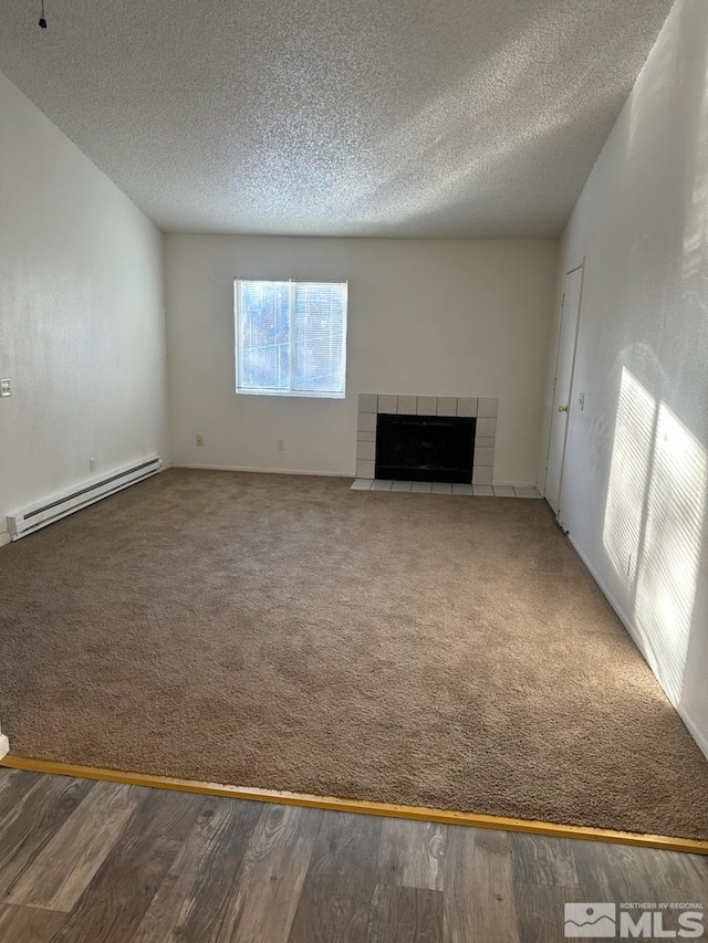 unfurnished living room with wood-type flooring, a baseboard heating unit, a textured ceiling, and a fireplace