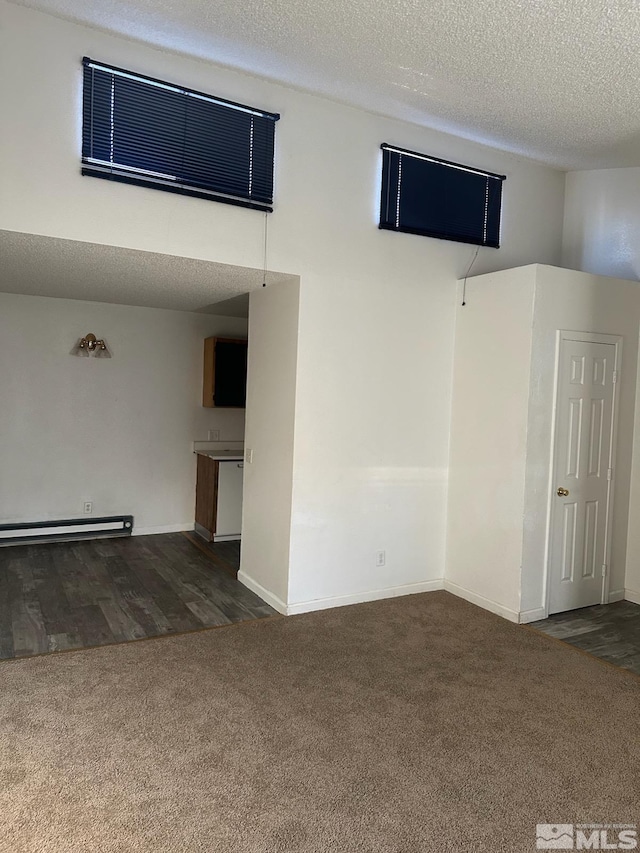 carpeted empty room featuring a baseboard radiator and a textured ceiling