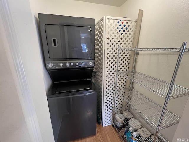 washroom with hardwood / wood-style flooring and stacked washer and clothes dryer