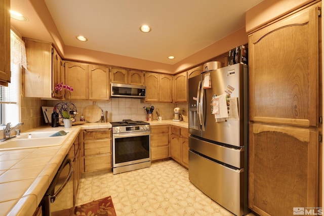 kitchen featuring stainless steel appliances, tasteful backsplash, sink, and tile countertops