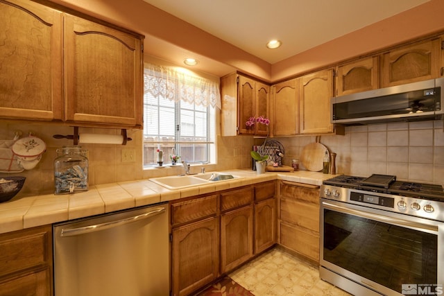 kitchen featuring appliances with stainless steel finishes, tile counters, sink, and decorative backsplash