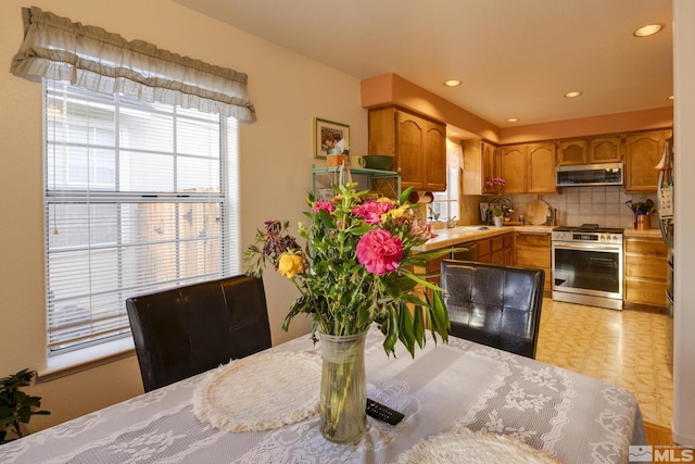 kitchen with tasteful backsplash, sink, stainless steel gas range, and exhaust hood