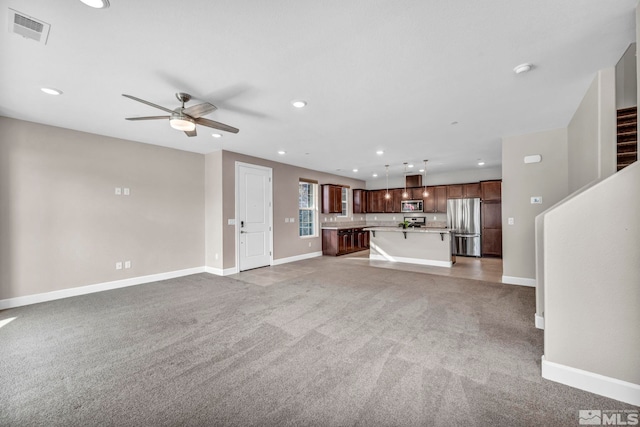 unfurnished living room with ceiling fan and carpet