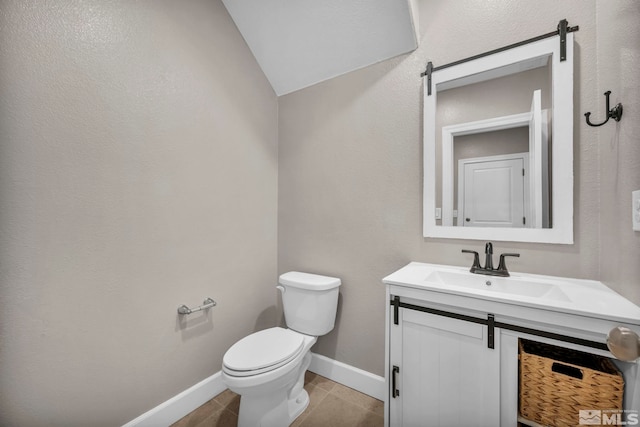 bathroom with vanity, toilet, tile patterned flooring, and vaulted ceiling