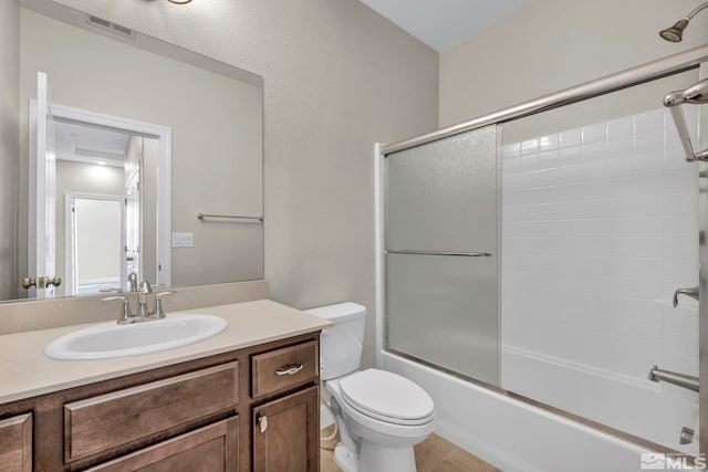 full bathroom with vanity, shower / bath combination with glass door, and toilet