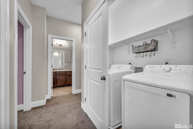 washroom featuring sink, washer and clothes dryer, and light colored carpet