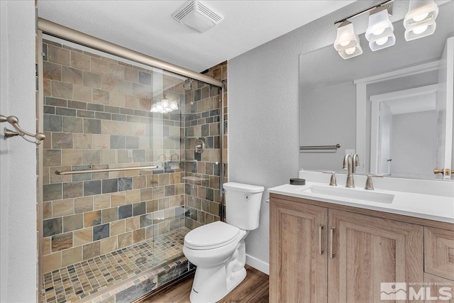 bathroom with vanity, hardwood / wood-style floors, a shower with shower door, and toilet