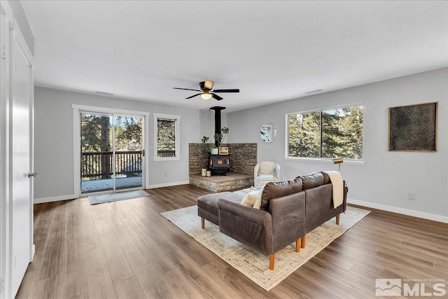 living room featuring dark hardwood / wood-style flooring, a wood stove, and a wealth of natural light