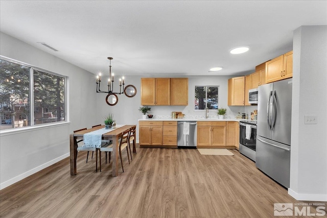 kitchen with sink, light hardwood / wood-style flooring, light brown cabinets, appliances with stainless steel finishes, and pendant lighting