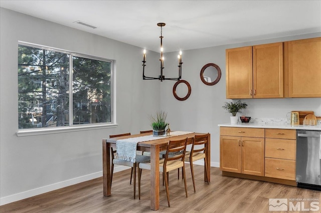 dining area with light hardwood / wood-style floors and a notable chandelier