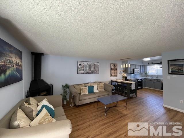 living room featuring a wood stove, wood-type flooring, and a textured ceiling