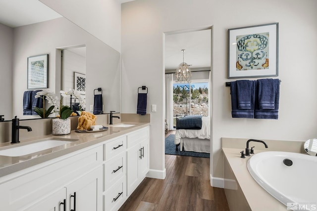 bathroom with hardwood / wood-style flooring, vanity, and a tub to relax in