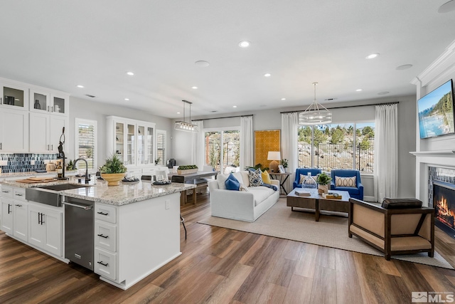 kitchen featuring sink, a kitchen island with sink, hanging light fixtures, and white cabinets