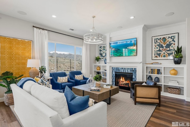 living room featuring a tiled fireplace, hardwood / wood-style floors, and a chandelier