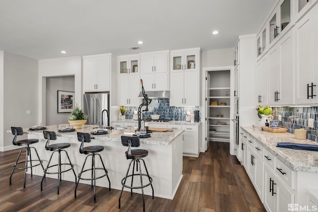 kitchen featuring appliances with stainless steel finishes, a breakfast bar, sink, white cabinets, and a kitchen island with sink