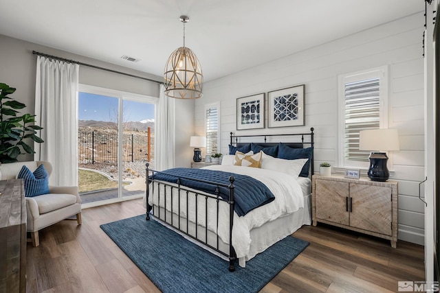 bedroom with hardwood / wood-style floors, access to outside, and a chandelier