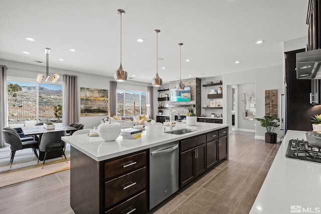 kitchen featuring sink, hanging light fixtures, a center island with sink, dishwasher, and black gas stovetop