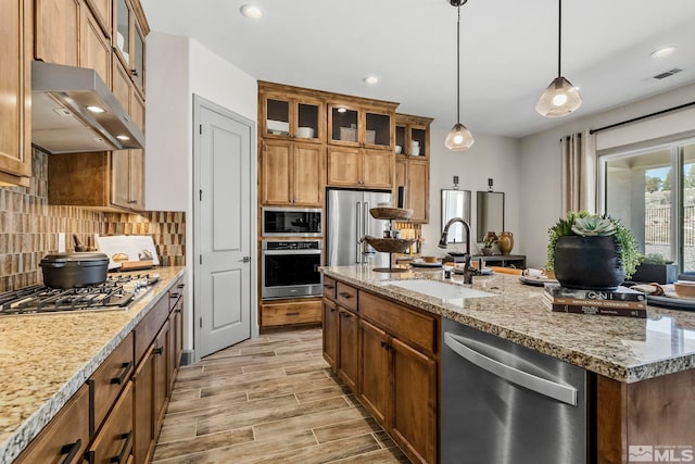 kitchen featuring sink, light stone counters, decorative light fixtures, appliances with stainless steel finishes, and decorative backsplash