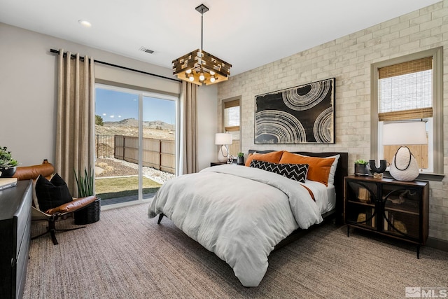 carpeted bedroom with brick wall and access to outside