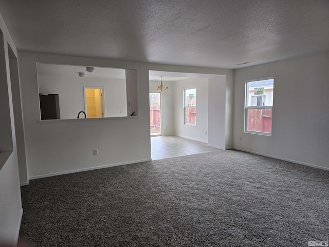 unfurnished living room featuring carpet, a textured ceiling, and an inviting chandelier