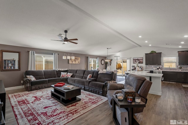 living room featuring lofted ceiling with beams, sink, ceiling fan with notable chandelier, and hardwood / wood-style floors