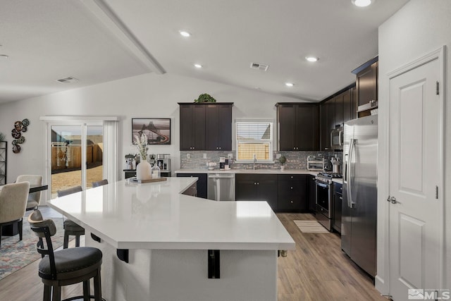 kitchen with appliances with stainless steel finishes, tasteful backsplash, lofted ceiling with beams, sink, and a center island